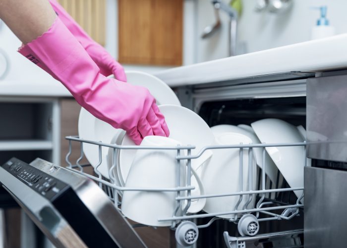 housewife taking out clean dishware from dishwasher at home kitchen